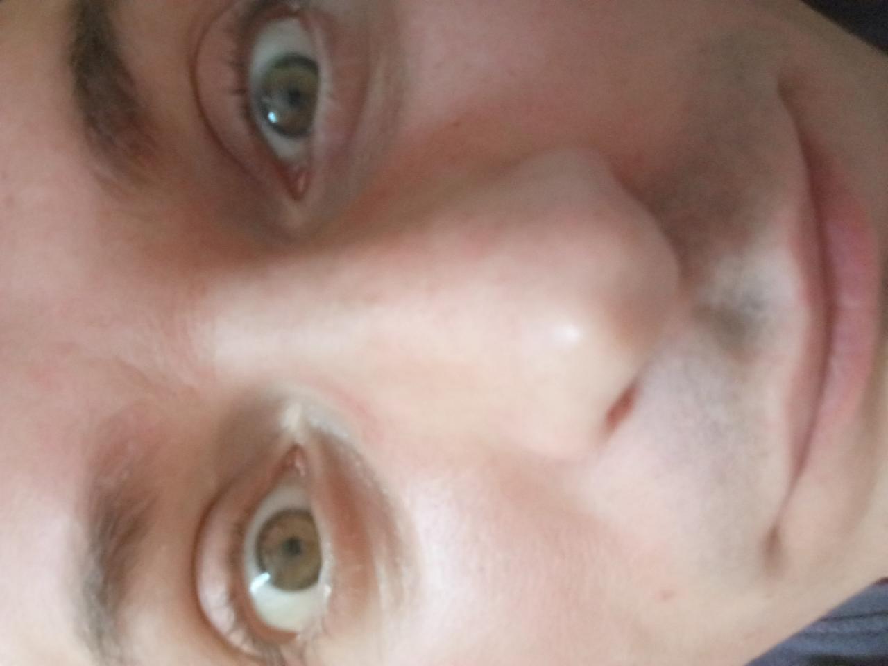 Zbliżenie na twarz mężczyzny z jasną karnacją, ukazujące jego oczy, nos i usta. Zdjęcie obrócone, z nietypowej perspektywy.