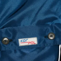 Fragment niebieskiej odzieży roboczej z kieszenią zapinaną na dwa guziki i naszywką z logo KOFPOL