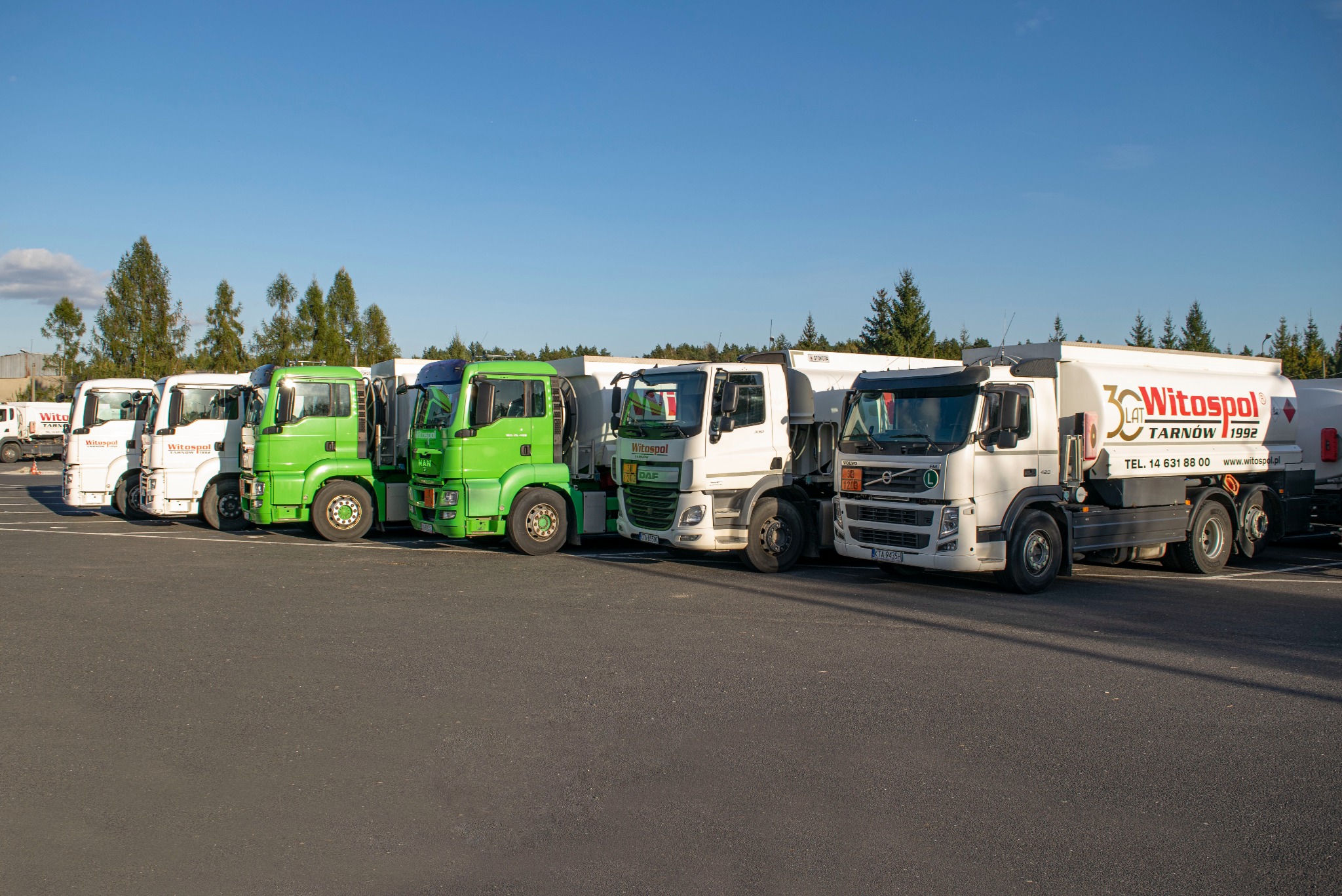 Flota cystern w barwach firmy Witospol, w tym zielone MAN i białe DAF, zaparkowana na placu. Na cysternach logo firmy i informacja o 30-leciu działalności.