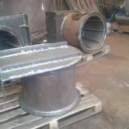 Elementy konstrukcji stalowej, prawdopodobnie wentylacyjne, spawane na paletach w warsztacie, widoczne ślady po spawaniu