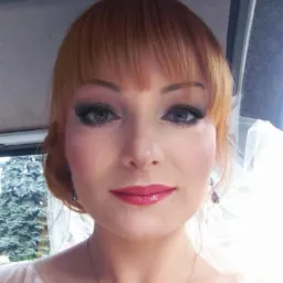 Portret kobiety z rudymi włosami i profesjonalnym makijażem ślubnym: mocne smoky eyes, r&oacute;żowe usta, delikatna biżuteria i welon. Widok z bliska.