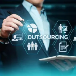 Mężczyzna w garniturze wskazujący na tablet z grafiką przedstawiającą ikony związane z zarządzaniem, personelem i danymi.