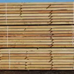 Stos świeżo przetartego drewna budowlanego, zabezpieczony białym sznurkiem, ułożony na zewnątrz w pobliżu tartaku.