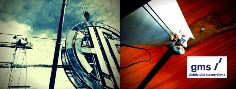 Montaż wielkoformatowego logo firmy na wysokości z użyciem dźwigu i rusztowań, widoczny pracownik na rusztowaniu oraz logo 'gms / alpinistyka przemysłowa'.