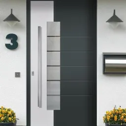 Nowoczesne drzwi wejściowe w Kamienicy Królewskiej, z szarymi panelami i długim, srebrnym uchwytem, otoczone kwiatami w donicach i oświetlone lampami.