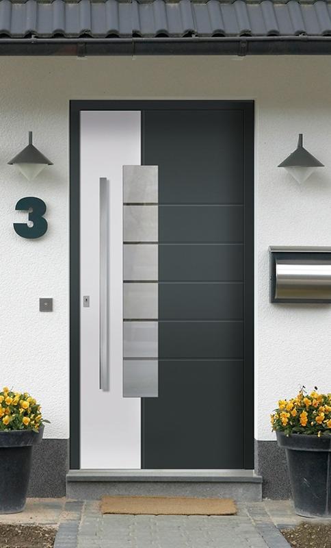 Nowoczesne drzwi wejściowe w Kamienicy Królewskiej, z szarymi panelami i długim, srebrnym uchwytem, otoczone kwiatami w donicach i oświetlone lampami.