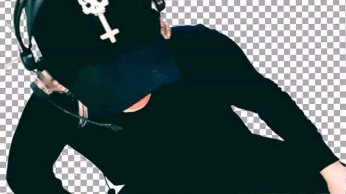 Osoba w czarnym stroju i słuchawkach z mikrofonem, nosząca czapkę z symbolem krzyża i czaszki, na tle transparentnym.