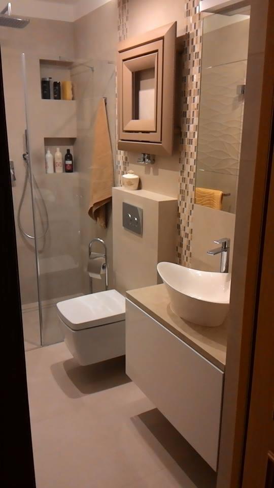 Nowoczesna łazienka w odcieniach beżu z kabiną prysznicową typu walk-in, podwieszaną toaletą i umywalką nablatową w kształcie łzy.