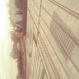 Wylane fundamenty z widocznym zbrojeniem, w tle domy jednorodzinne. Ujęcie z góry, w ciepłej tonacji.