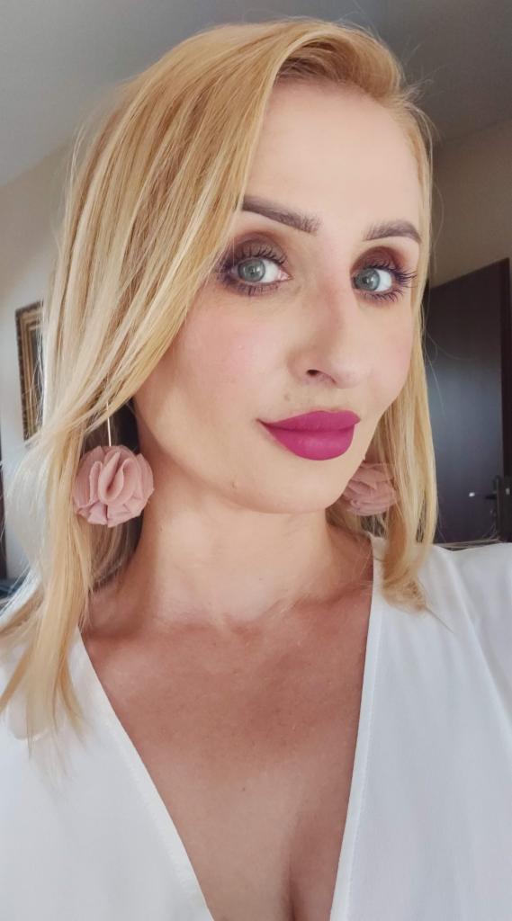 Portret kobiety z blond włosami i różową szminką, Częstochowa. Uśmiech, kolczyki i biała bluzka. Lekcja angielskiego online, prezentacja nauczyciela.