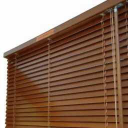 Zamknięte poziome żaluzje w kolorze ciemnego drewna, widoczne sznurki i mechanizm mocujący, na białym tle.