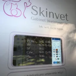 Szyld gabinetu weterynaryjnego Skinvet z godzinami otwarcia i numerem telefonu, widoczny symbol psa i kota w logo.