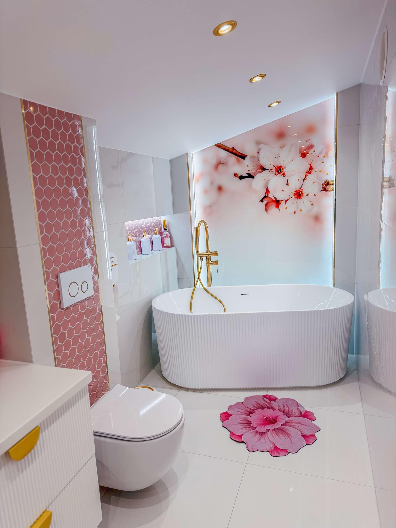 Nowoczesna łazienka w Borzechowie z wanną wolnostojącą, różową mozaiką heksagonalną i motywem kwiatowym na ścianie.