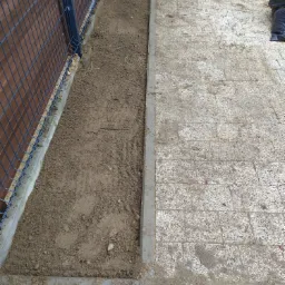 Przygotowany teren pod trawnik z rolki, obok ułożona kostka brukowa, widoczne ogrodzenie panelowe.