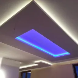 Podwieszany sufit z płyt kartonowo-gipsowych z oświetleniem LED: białe światło obrysowe i centralne niebieskie światło.