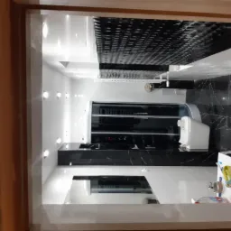 Nowoczesna łazienka z czarno-białymi płytkami marmurkowymi na ścianach i suficie, widok zza futryny drzwi, oświetlenie punktowe i biała armatura.