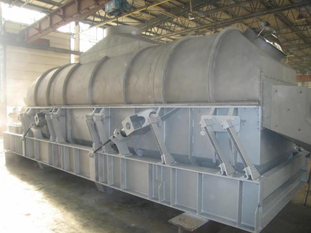 Duża, metalowa konstrukcja przemysłowa, prawdopodobnie element linii produkcyjnej, z widocznymi spawami i elementami mocującymi, w hali oświetlonej światłem dziennym.