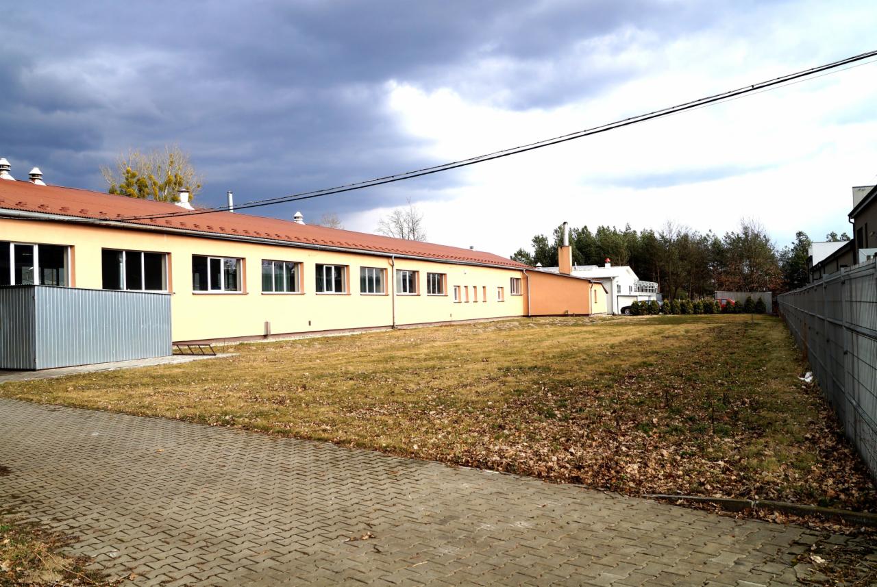 Budynek warsztatu obróbki metali z pomarańczowym dachem i żółtymi ścianami, widok z zewnątrz na tle pochmurnego nieba.