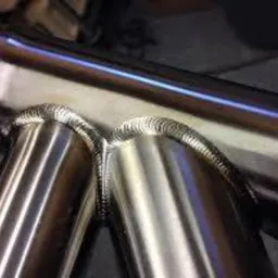 Błyszczące, precyzyjne spawy łączące rury z metalu, widoczne charakterystyczne ślady po spawaniu TIG.