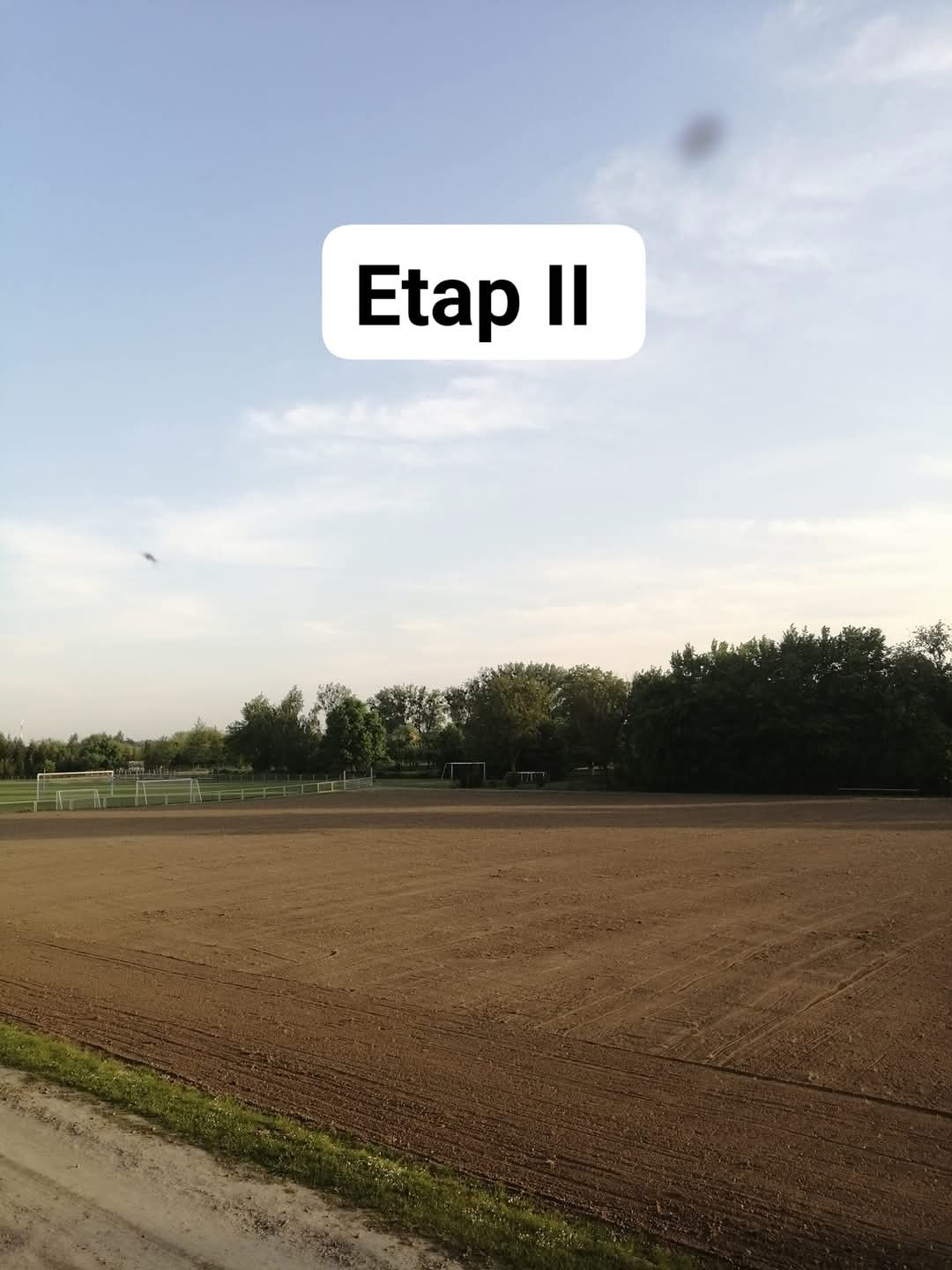 Przygotowany teren pod zasiew trawy na boisku sportowym, widoczne bramki, etap II prac ziemnych.