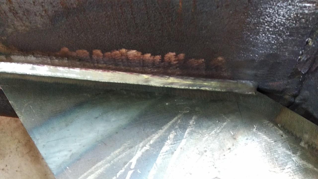 Spoina łącząca elementy metalowe, widoczne ślady korozji na krawędziach, surowe wykończenie.