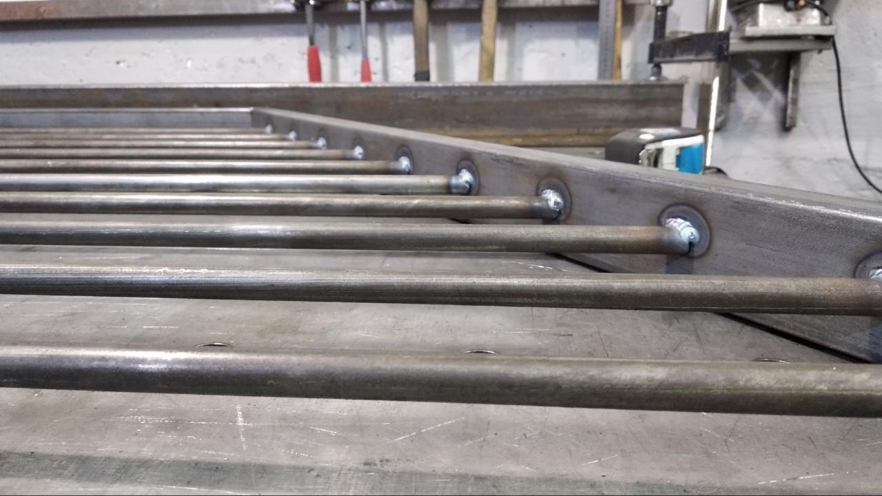 Metalowa konstrukcja z rur, z widocznymi spawami, wykonana w warsztacie.