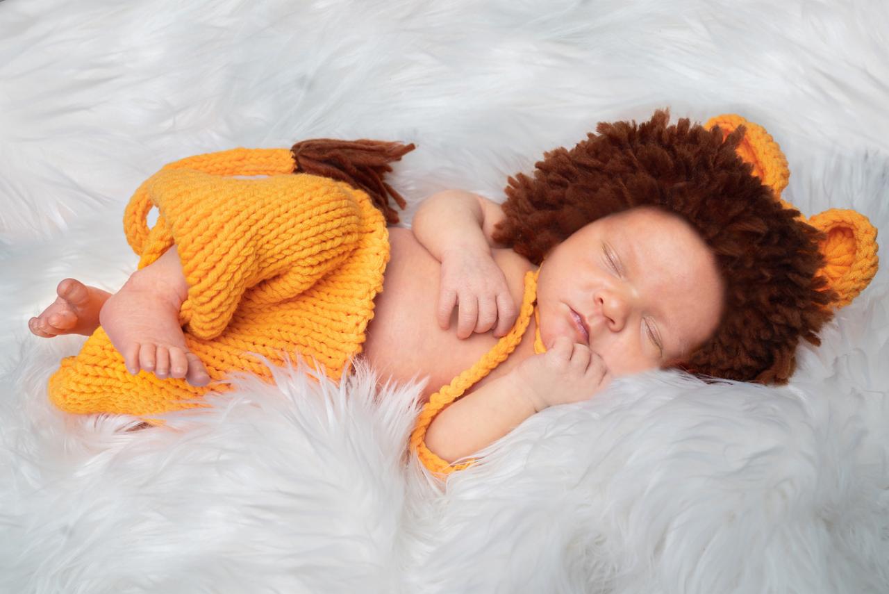 Śpiący noworodek w kostiumie lwa na puszystym, białym tle, wykonany w Czudcu.