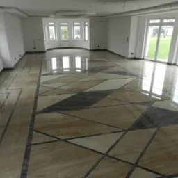 Nowoczesna, błyszcząca podłoga z kamienia w geometryczne wzory w przestronnym, jasnym wnętrzu z dużymi oknami.