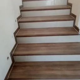 Schody wykończone płytkami ceramicznymi i panelami drewnopodobnymi, widok z dołu.