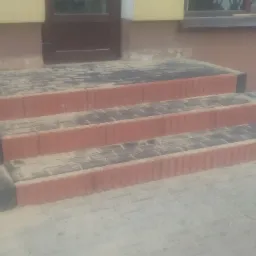 Nowo ułożone, trzy stopniowe schody wejściowe z kostki brukowej w odcieniach szarości i czerwieni, z czarnymi obrzeżami, posypane piaskiem, prowadzące do drzwi wejściowych budynku.