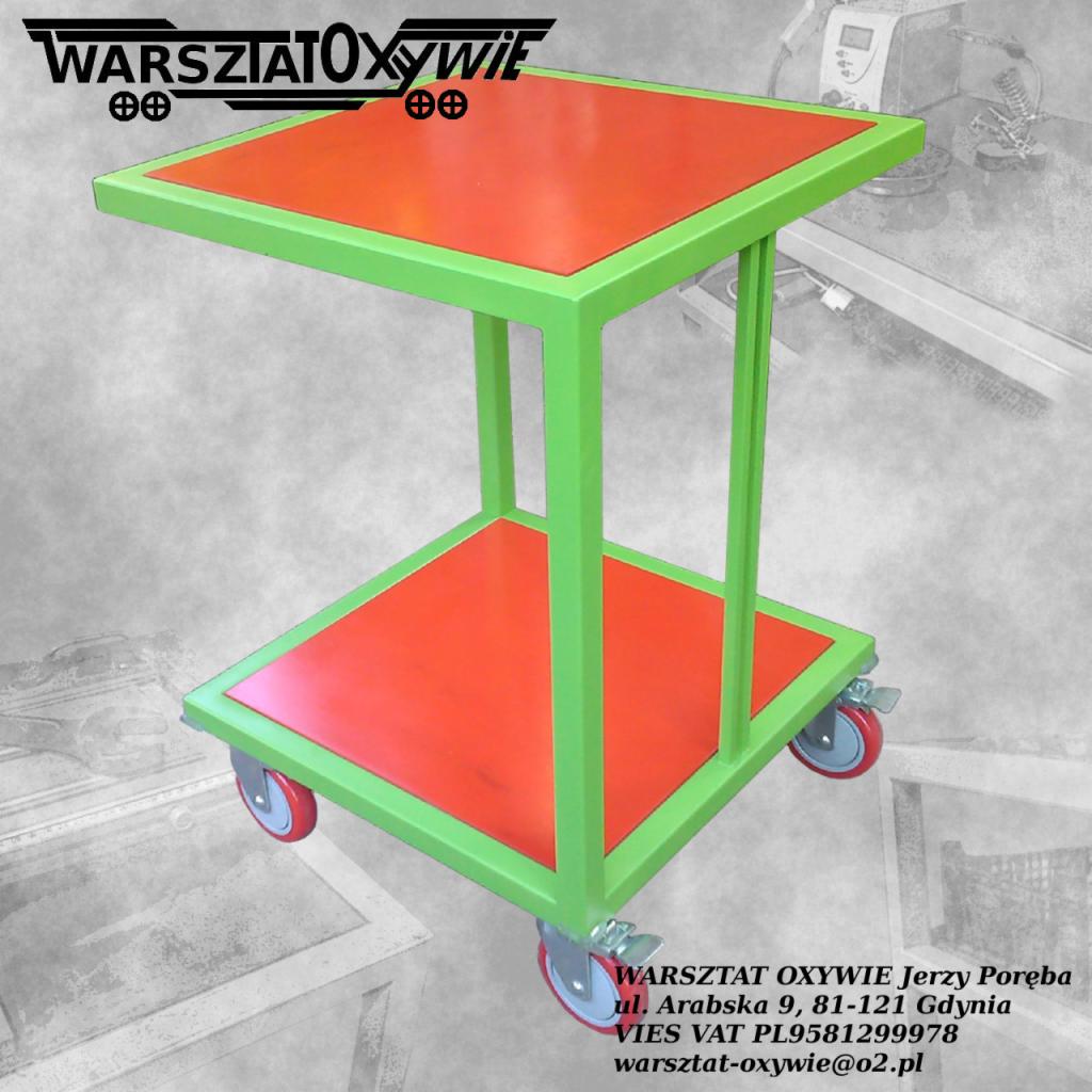 Wózek warsztatowy z dwoma poziomami, rama z profili pomalowana na zielono, blaty w kolorze pomarańczowym, wyposażony w cztery koła z hamulcami. W tle widoczne wyposażenie warsztatu.