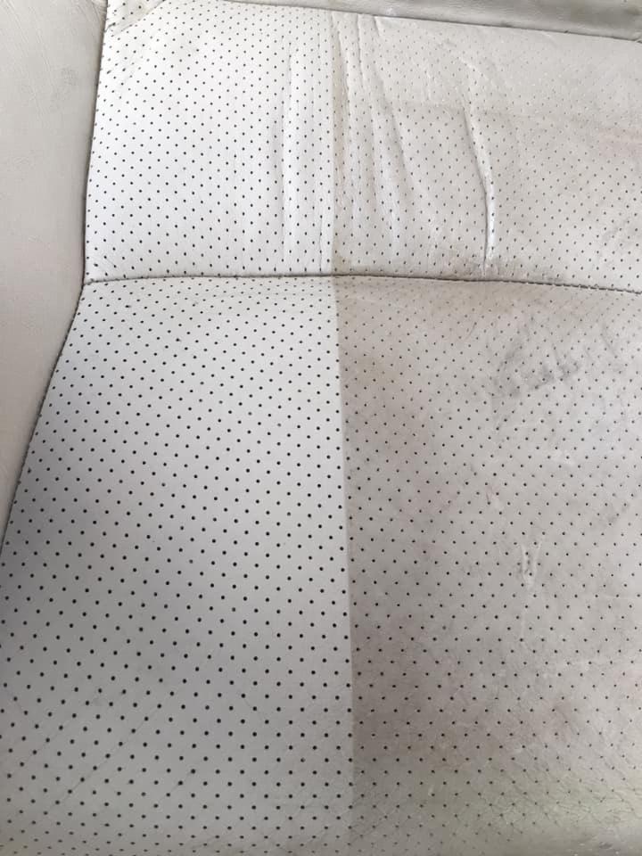 Fragment białej, perforowanej skórzanej tapicerki samochodowej, widoczny podział na czystą i zabrudzoną część, ukazujący efekt czyszczenia.