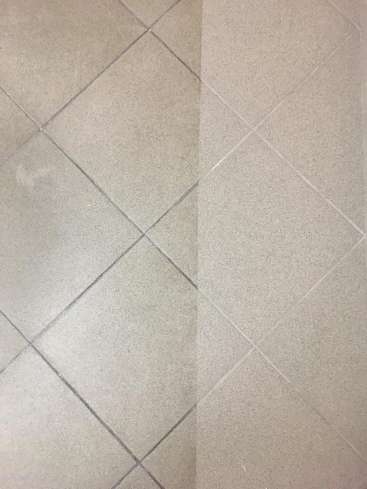 Fragment podłogi z jasnych, kwadratowych płytek ceramicznych, z widoczną różnicą w czystości - lewa strona zabrudzona, prawa świeżo umyta.