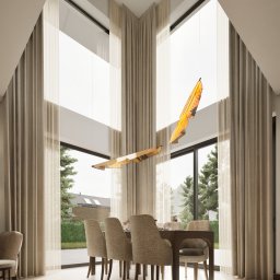 JoinAnnaDesign Anna Pawikowska - Jasna jadalnia z wysokimi oknami i beżowymi zasłonami. Nad stołem wisi nowoczesna lampa. Za oknem widok na zieleń i dom.