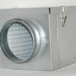 Metalowa skrzynka wentylacyjna z okrągłym otworem i kratką, widoczne nity mocujące, na białym tle.