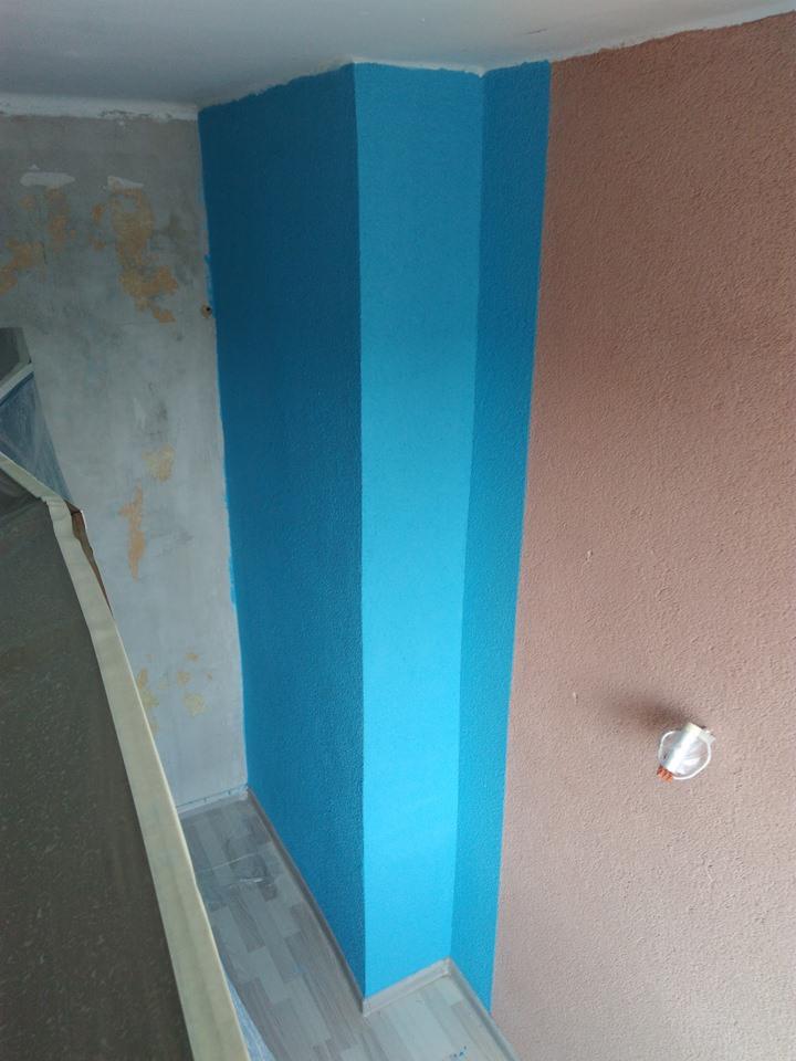 Fragment ściany po malowaniu: turkusowy narożnik z efektem ombre sąsiaduje z beżową ścianą o wyraźnej fakturze, widoczne zabezpieczenia podłogi taśmą malarską, surowy fragment ściany w tle.