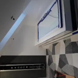 Nowoczesna łazienka w trakcie remontu: oszklona kabina prysznicowa z niebieską taśmą malarską zabezpieczającą, geometryczne płytki na ścianie, czarna ściana z chromowaną armaturą