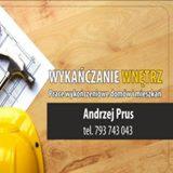 Wizytówka firmy wykończeniowej na tle drewnianej powierzchni z fragmentem planu i kasku budowlanego. Widoczny młotek.