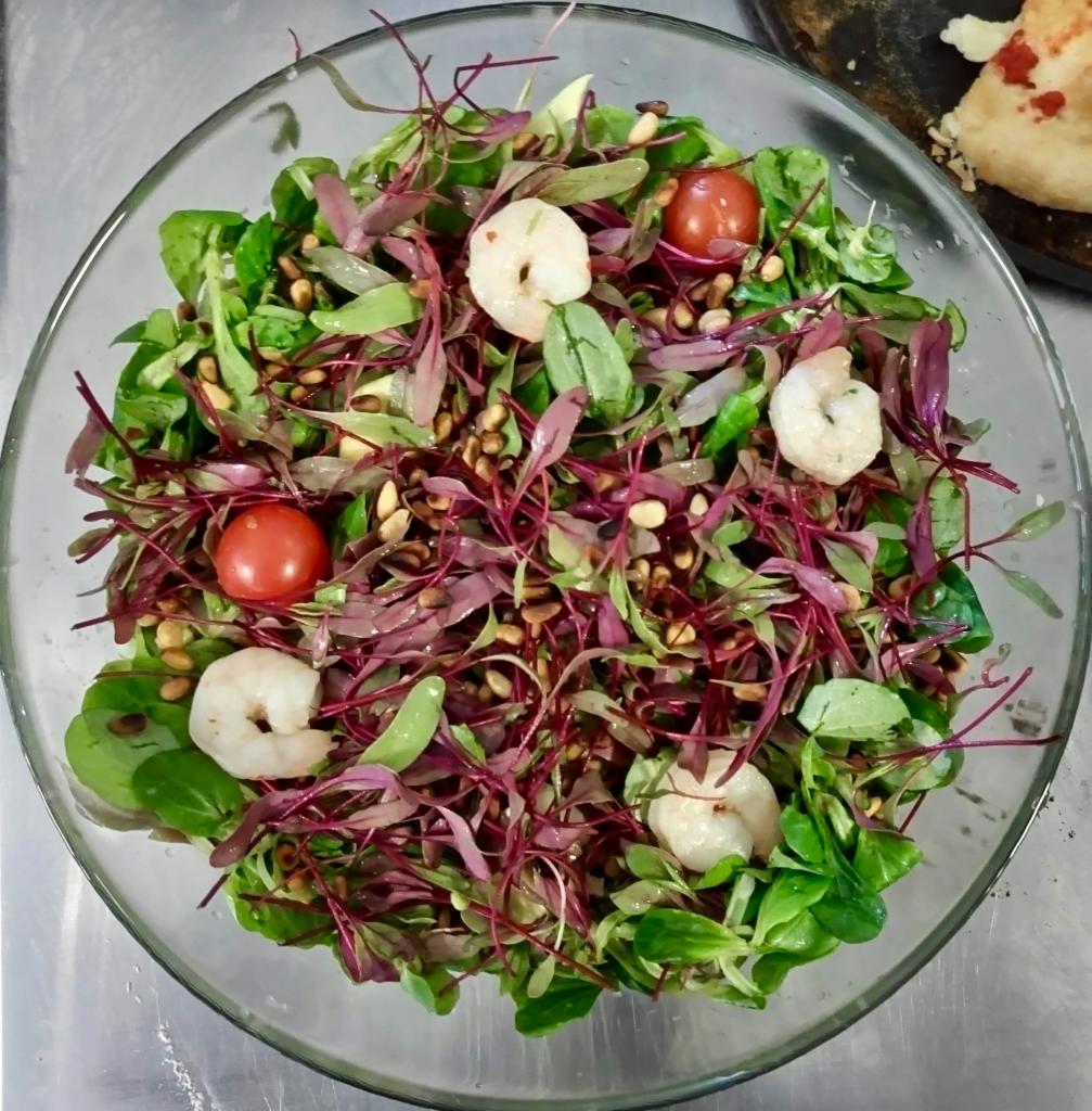 Szklana misa z kolorową sałatką z krewetkami, pomidorkami cherry i orzeszkami pinii, przygotowana przez firmę cateringową z Krakowa.