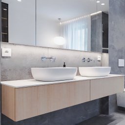 Wyskkuchnie - Nowoczesna łazienka z dwoma owalnymi umywalkami nablatowymi i szafką pod umywalkę z jasnego drewna na tle ściany z szarego kamienia i dużego lustra.