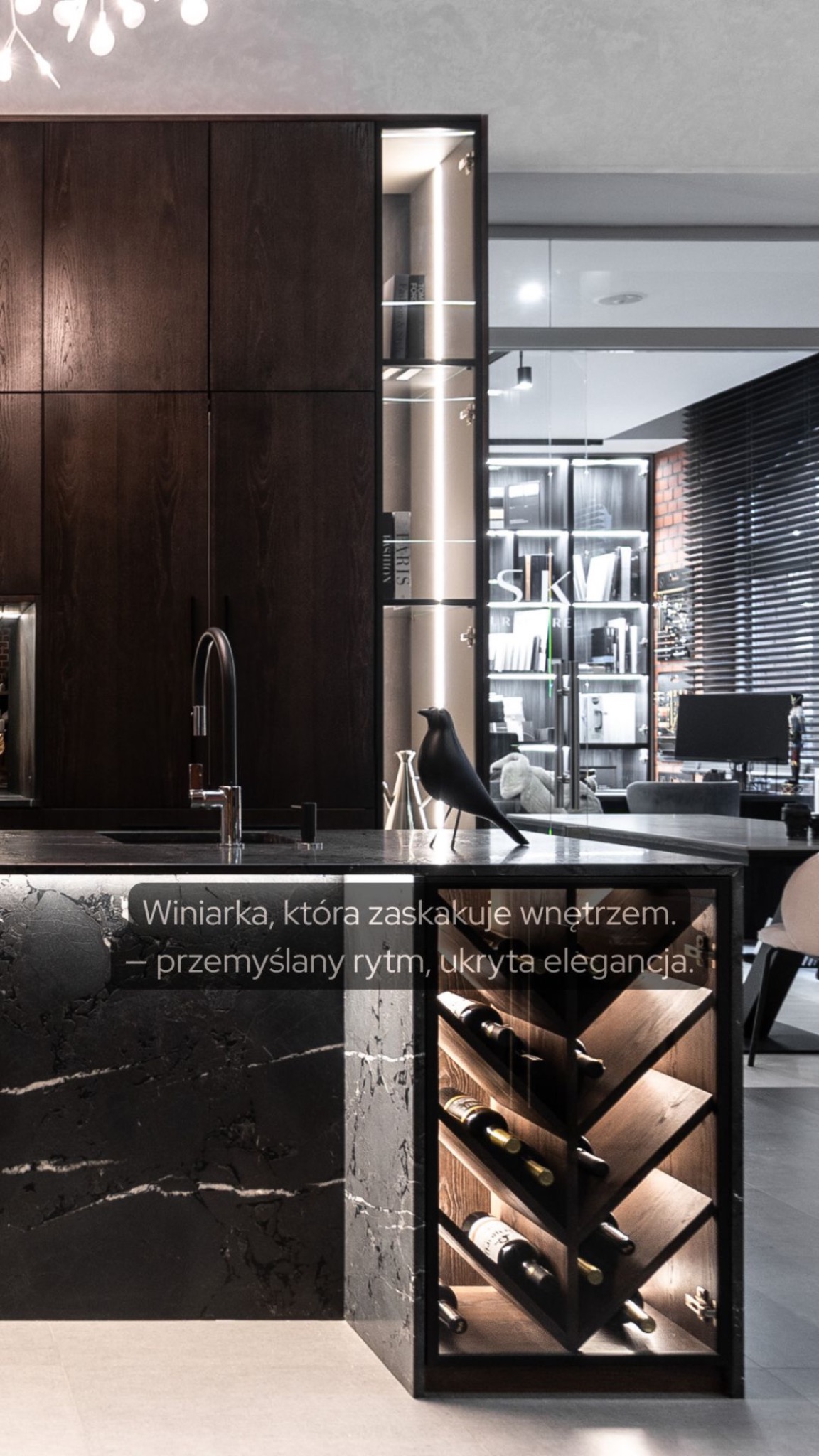 Nowoczesna kuchnia z ciemnego drewna i czarnego kamienia. Winiarka z oświetleniem LED i ekspozycją na butelki. Dekoracyjny ptak na blacie.