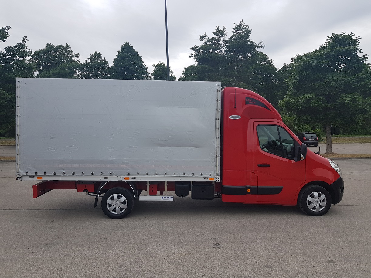 Czerwony samochód dostawczy z plandeką na parkingu, widok z boku, z napisem 'Heavy Truck' nad szybą.