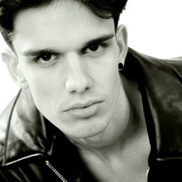 Fotografia niekonwencjonalna Ilona Bałon - Czarno-biały portret młodego mężczyzny w skórzanej kurtce, z kolczykiem w uchu, spoglądającego w górę, z mocnym oświetleniem i wyraźnymi rysami twarzy.