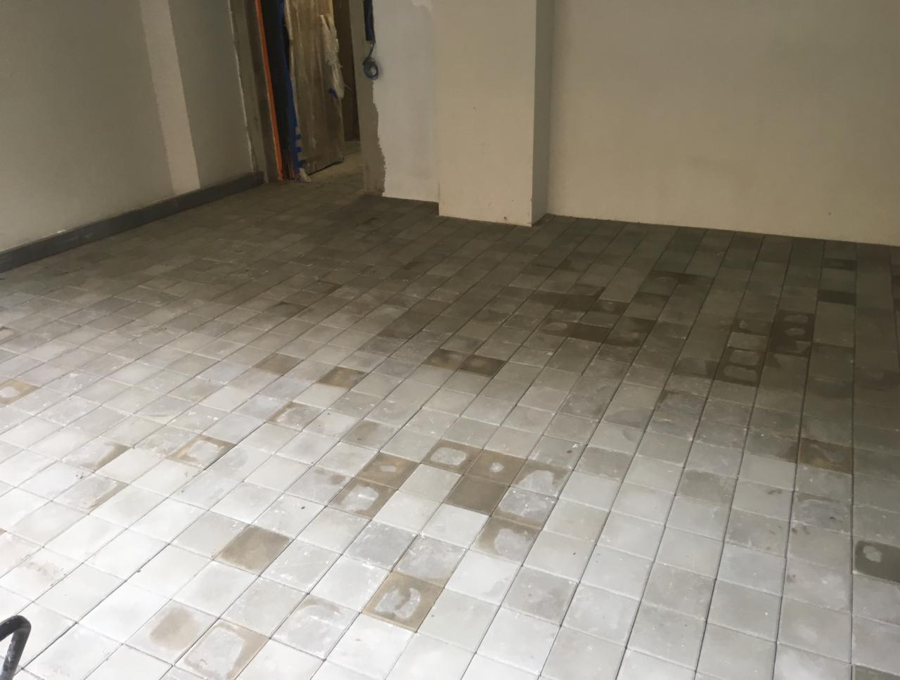 Wnętrze w trakcie układania szarej kostki brukowej w Markach, widoczne ślady zaprawy na powierzchni. Częściowo ułożona podłoga w surowym stanie.