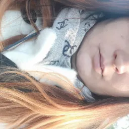 Portret kobiety z długimi, ombre włosami, szarym szalikiem i jasnymi oczami, uchwycony z bliska.