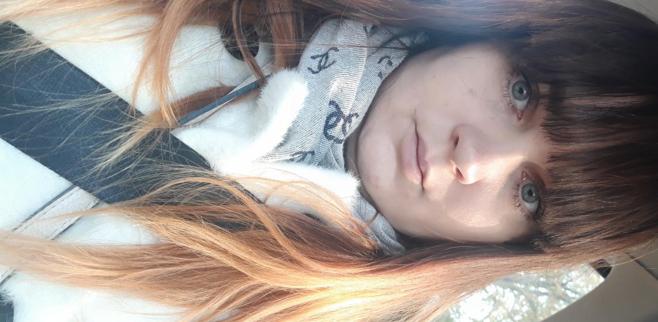 Portret kobiety z długimi, ombre włosami, szarym szalikiem i jasnymi oczami, uchwycony z bliska.