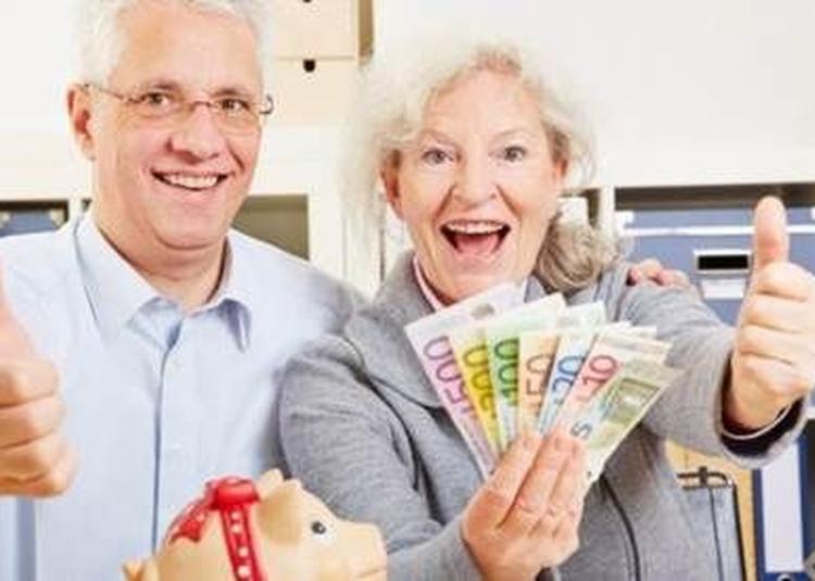 Uśmiechnięci seniorzy trzymający wachlarz banknotów euro i pokazujący kciuki w górę, obok świnki skarbonki z czerwoną kokardką.
