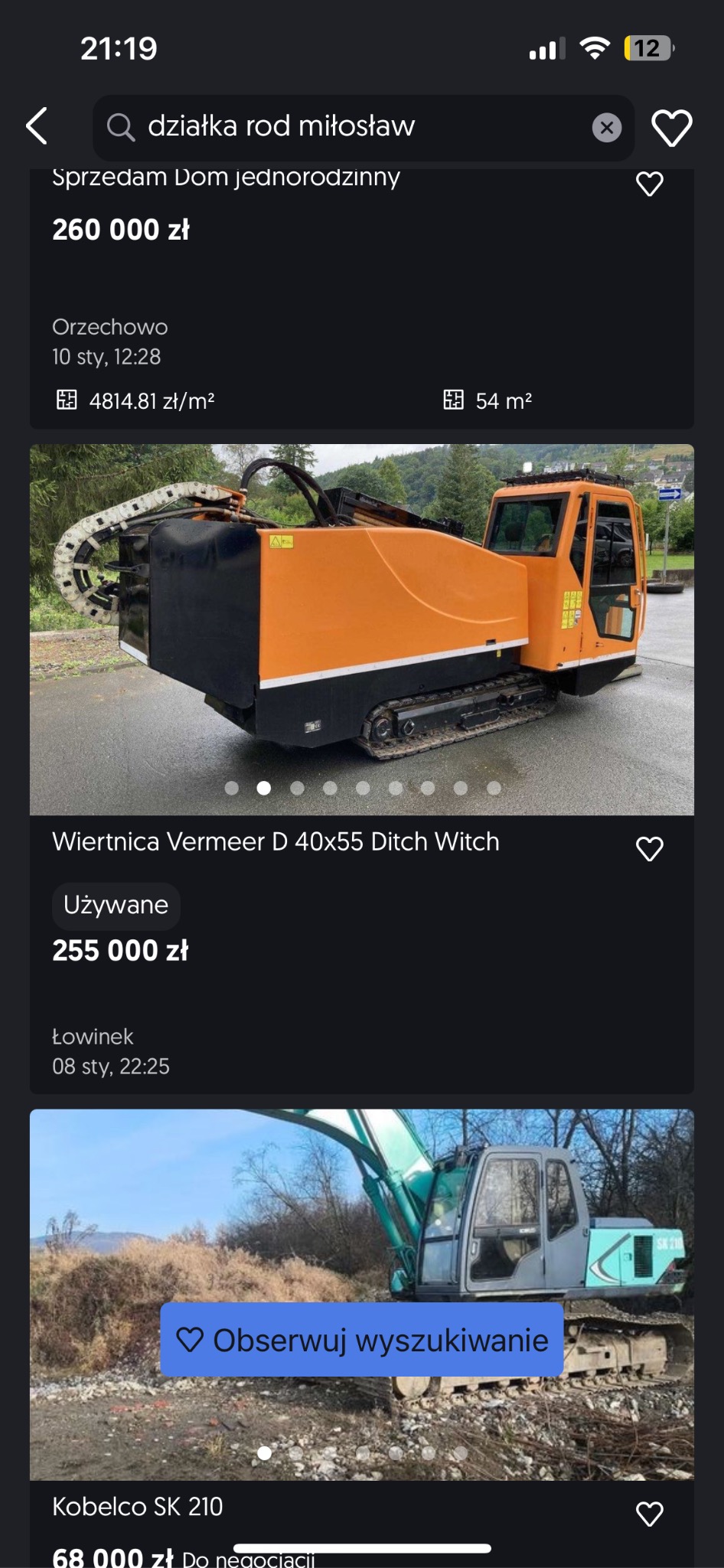 Pomarańczowo-czarna wiertnica Vermeer D 40x55 Ditch Witch na gąsienicach, zaparkowana na asfaltowej powierzchni, z zielenią w tle.