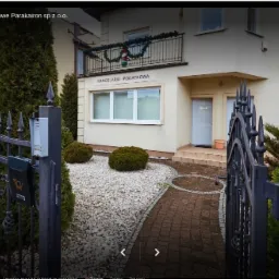 Budynek biura rachunkowego z kutą bramą, tabliczką 'Kancelaria Podatkowa' nad wejściem i świąteczną dekoracją na balkonie.