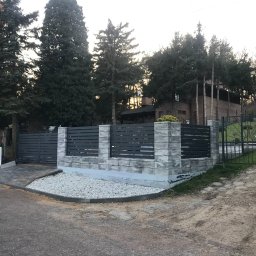 PHU SUN-TEL Cezary Dobrzyński - Nowoczesne ogrodzenie panelowe z poziomymi przęsłami w kolorze grafitowym, osadzone na murku z szarej kostki, z widocznym fragmentem bramy wjazdowej i zielenią w tle.